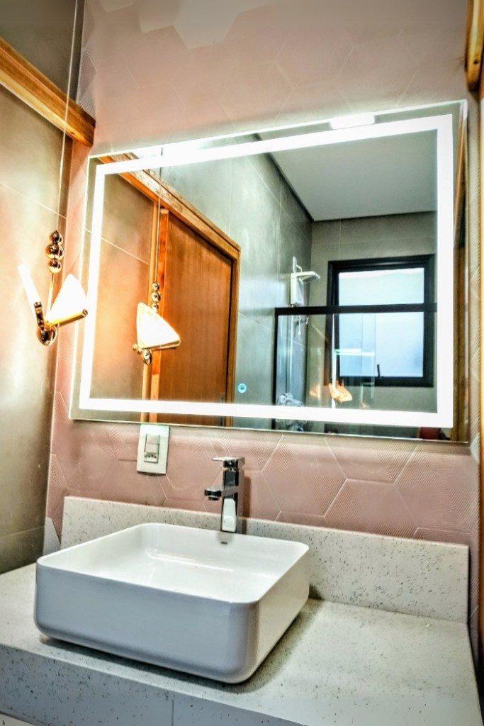 Espelho retangular com iluminação LED frontal em banheiro planejado.