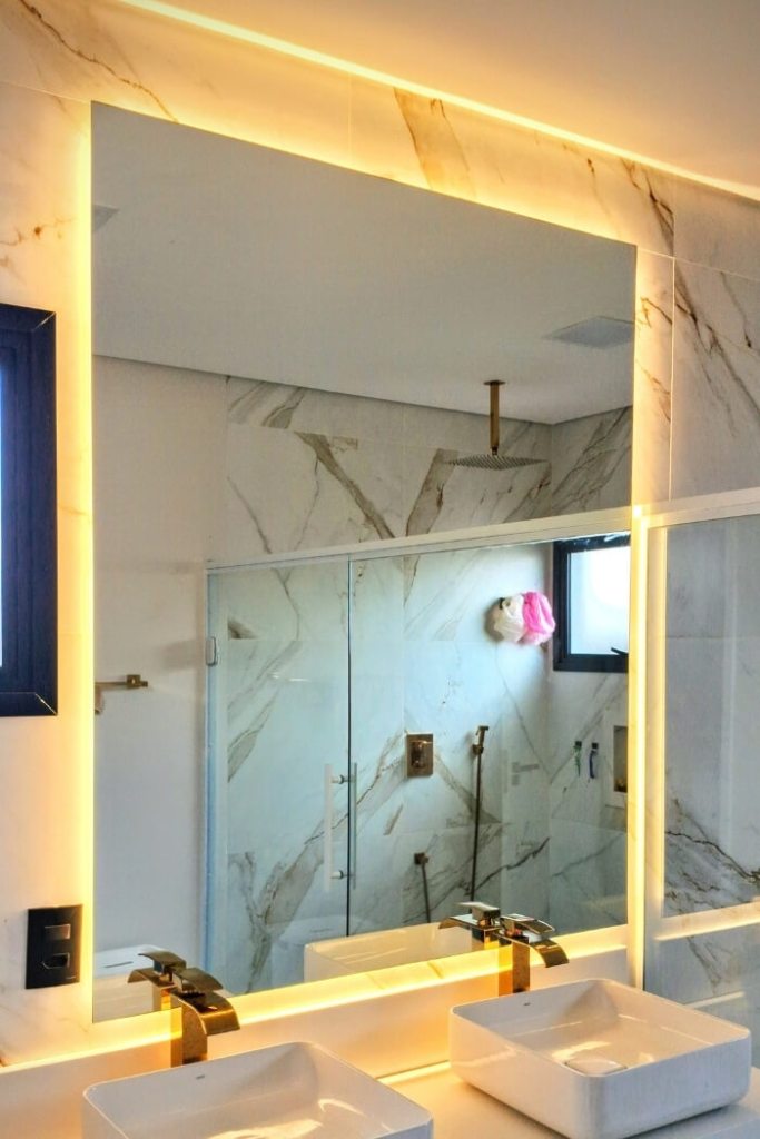 Espelho com LED amarelo retangular em banheiro luxuoso com revestimento marmorizado em Sorocaba.